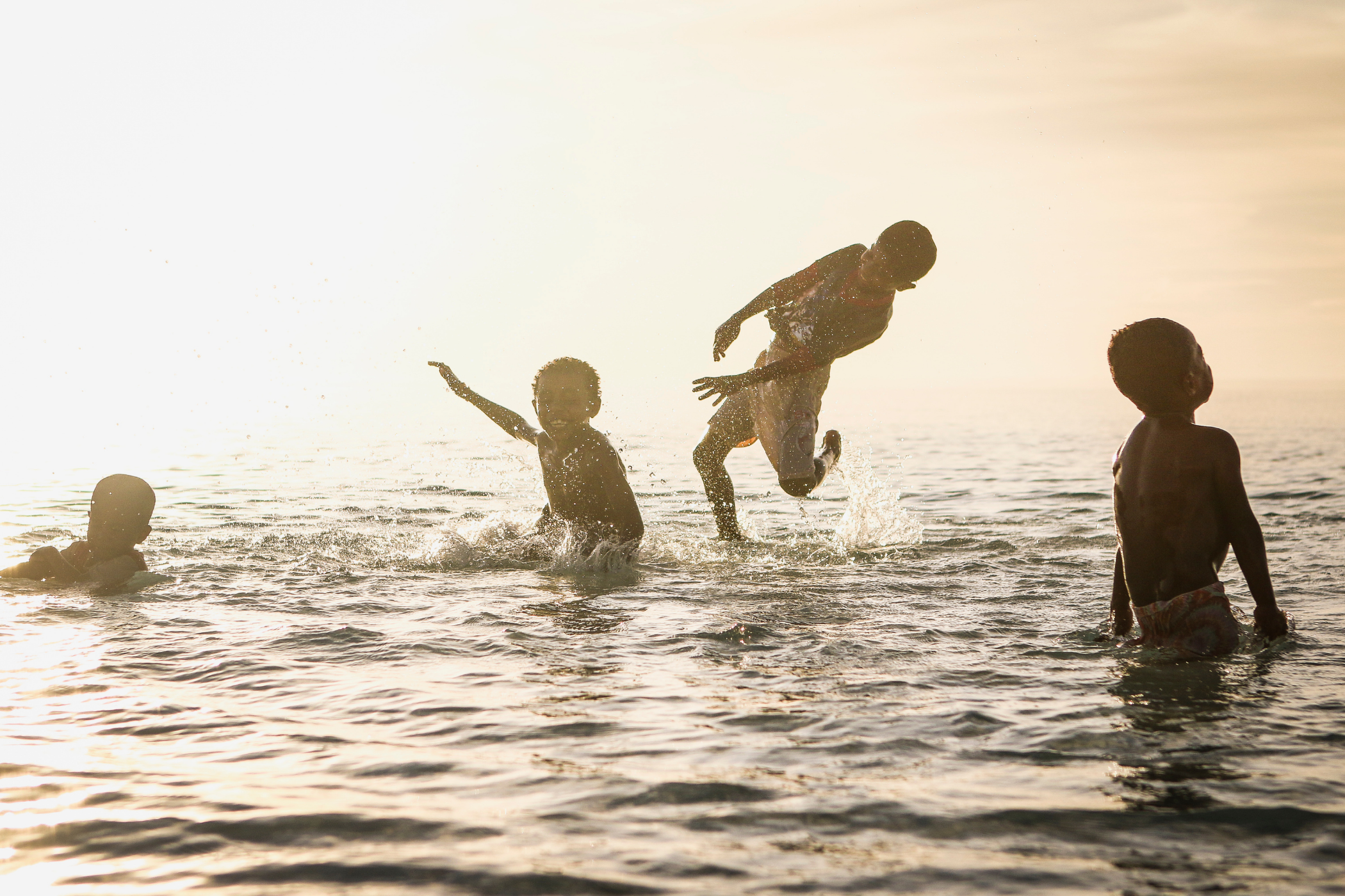 Children playing in water under a large leaf